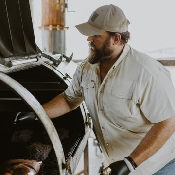 man with tan short sleeve shirt opening grill