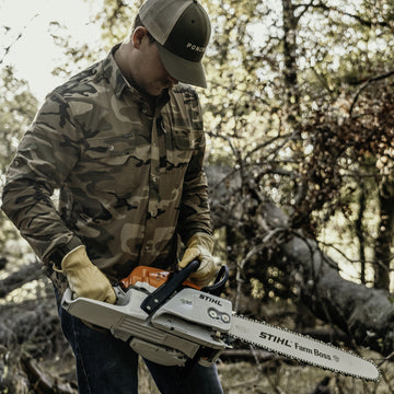 man wearing long sleeve camo shirt with chainsaw