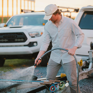 man spraying fishing poles in grey and white plaid shirt