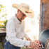 man cooking steaks in long sleeve grey and white plaid button up