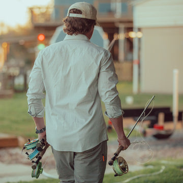 man carrying fly rods in grey and white plaid button up