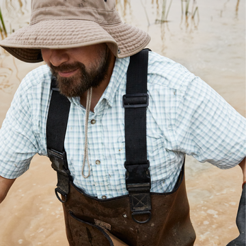 man in water wearing green grid button up short sleeve shirt