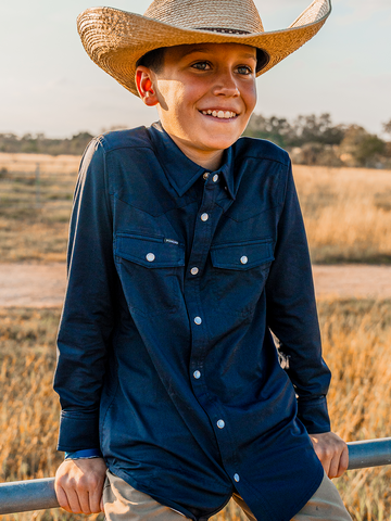 Boy in blue shirt sitting on fence