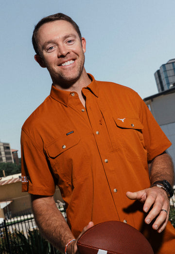 Man wearing The San Jacinto rust-colored outdoor shirt holding a football outdoors