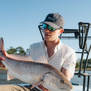 man holding fish with made for the outdoors dad hat
