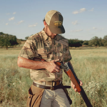 Man with shotgun wearing moss agave trucker hat