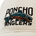 Embroidery of a colorful fish with the words "Poncho Anglers" stitched on a beige fabric surface.