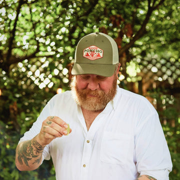 man wearing ocotillo trucker hat squeezing lime