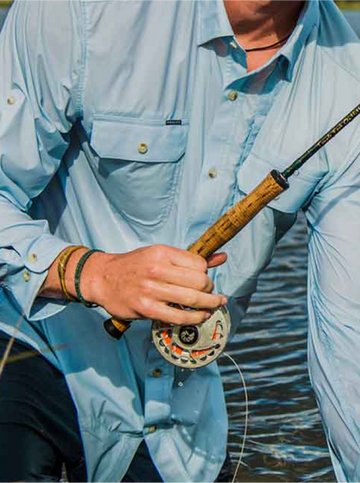 Man in blue shirt holding fly rod