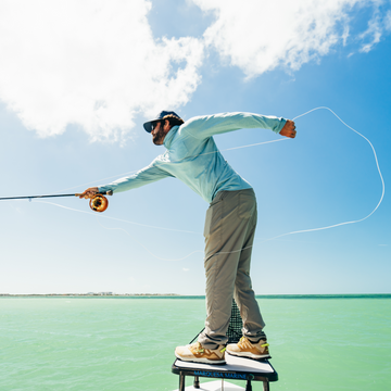 man casting fishing rod wearing salty teal hoodie