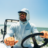 man driving boat wearing salty teal hooodie