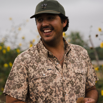 The Popper Hat worn by a smiling man in a patterned shirt outdoors