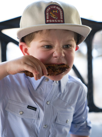 Kid eating chicken in a blue microcheck kid's shirt