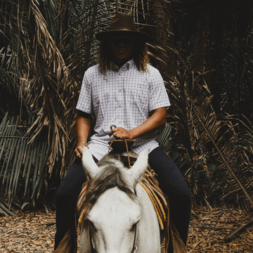 Man riding horse in button down short sleeve shirt