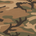 Olive green, tan, and dark brown camouflage pattern with organic shapes and branch-like elements.