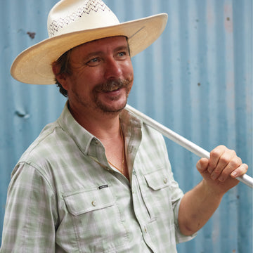 man smiling wearing green plaid shirt