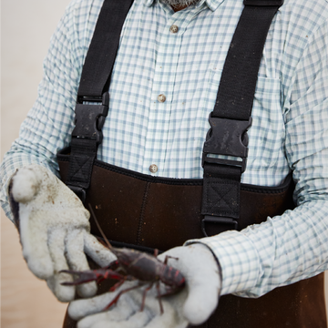 man holding crawfish in green and plaid long sleeve shirt