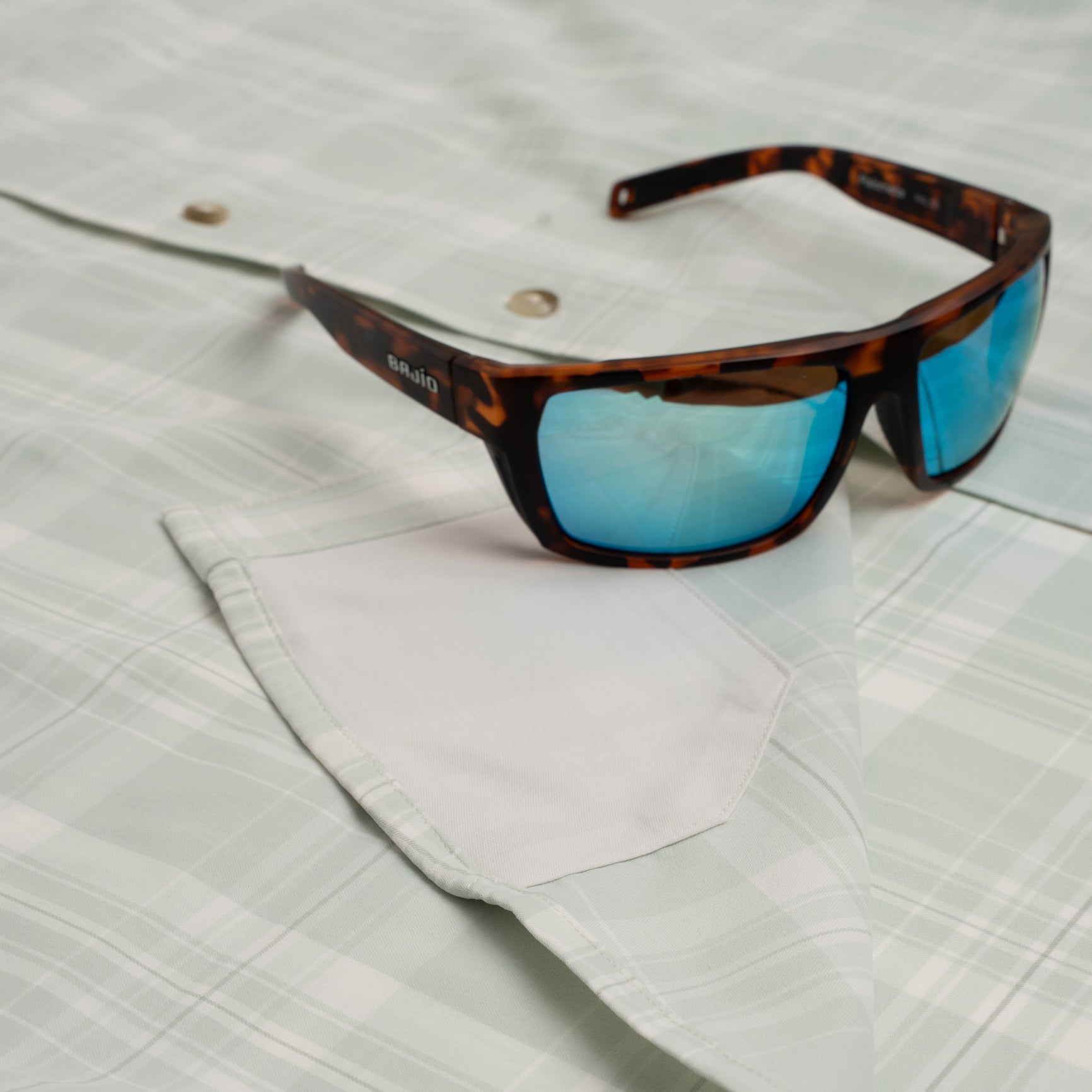 Photo of hidden sunglass pocket on green plaid button down shirt