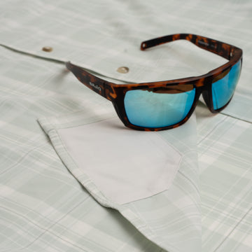 Sunglasses sitting on green plaid button down shirt