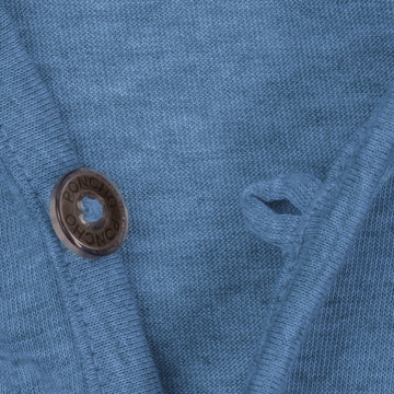 Close-up of a textured blue fabric with a brown button labeled Poncho and a matching buttonhole from The Spartina shirt.