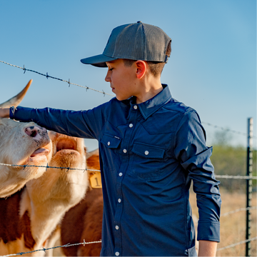 Boy petting a cow standing next to fence