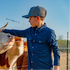 Boy petting a cow standing next to fence