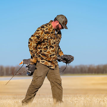 man carrying waterfowl decoys in old school camo flannel