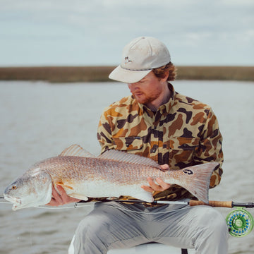 Man with tan mallard hat holding fish