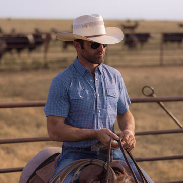 man riding horse wearing slate blue check short sleeve shirt