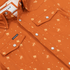 Close-up of an orange patterned shirt with snap buttons, highlighting the chest pockets and fabric texture of The 5th Year.