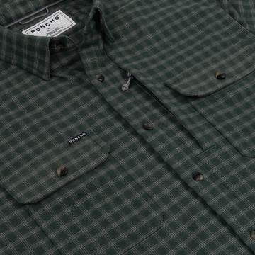 Close-up of The Acadia green plaid shirt with buttoned chest pockets and Poncho Outdoors label detail.