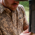 Close-up of a man wearing The Armadillo shirt with a nature-inspired pattern and a Poncho label on the chest pocket.