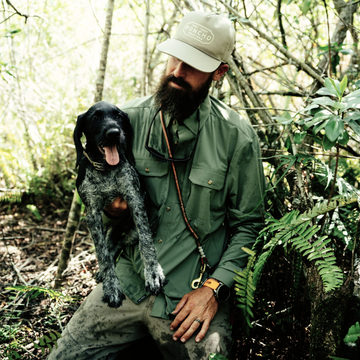 man holding dog wearing green long sleeve shirt