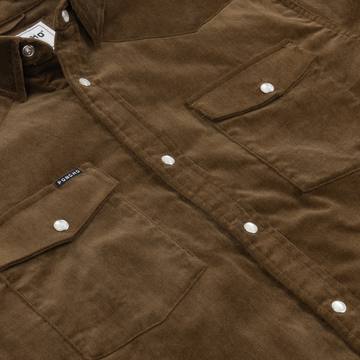 Close-up of brown corduroy fabric with snap buttons and stitched pockets on The Barnhart shirt