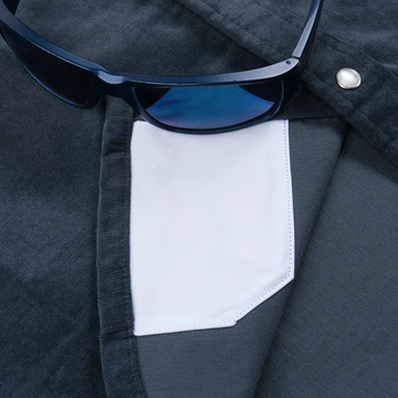 Close-up of a dark fabric shirt pocket with a white interior and a pair of dark sunglasses resting on top, featuring The Barton Springs.