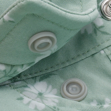 Close-up of light green floral fabric with snap buttons on The Bat Masterson shirt, highlighting durable stitching.