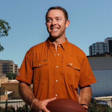 man holding football wearing orange Texas shirt