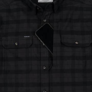 Close-up of The Black Canyon shirt with a phone partially tucked into the chest pocket, highlighting its functional design.