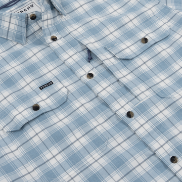 Close-up of a blue and white plaid shirt with buttoned chest pockets branded Poncho, named The Blue Bison