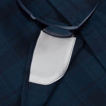 Close-up of dark plaid fabric and white inner pocket detail on The Blue Goose shirt with black sunglasses resting on top