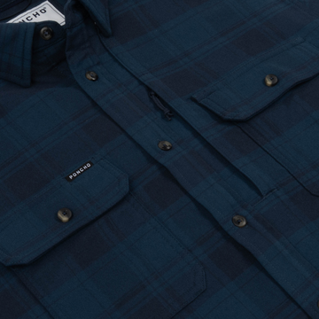 Close-up of The Blue Goose shirt in dark blue plaid with buttoned chest pockets and collar detailing