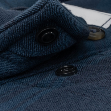 Close-up of dark blue fabric and snap buttons detail on The Blue Goose shirt, highlighting texture and design.