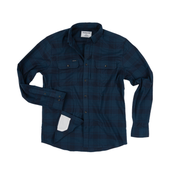The Blue Goose shirt in dark blue plaid with button-up front and chest pockets, styled for outdoors.