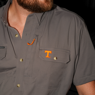 Close-up of a man wearing The Bluetick grey shirt with orange details and buttoned chest pockets