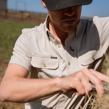 The Brown Bear tan mens outdoor shirt with snap buttons and chest pockets worn outdoors