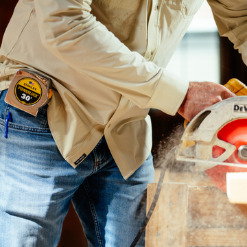 man wearing tan long sleeve shirt cutting wood