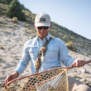 The Buckhorn shirt worn outdoors by an angler holding a landing net on a rocky hillside