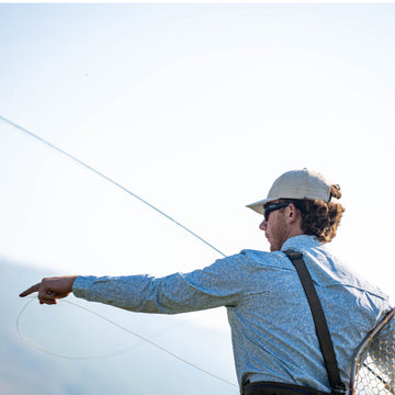 The Buckhorn blue patterned shirt worn by an angler casting a fishing line outdoors