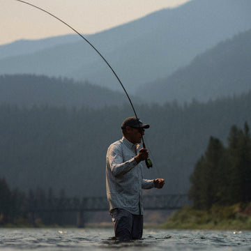 Man fly fishing wearing The Buffalo Ford shirt in mountain river outdoors