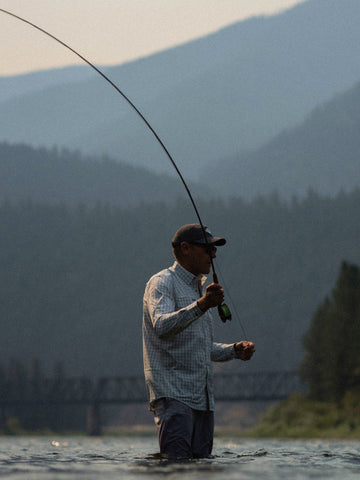Man fly fishing wearing The Buffalo Ford shirt in mountain river outdoors